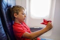 Little kid boy playing with red paper plane during flight on airplane Royalty Free Stock Photo