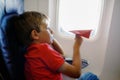 Little kid boy playing with red paper plane during flight on airplane Royalty Free Stock Photo