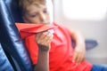 Little kid boy playing with red paper plane during flight on airplane Royalty Free Stock Photo