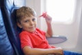 Little kid boy playing with red paper plane during flight on airplane Royalty Free Stock Photo