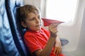 Little kid boy playing with red paper plane during flight on airplane Royalty Free Stock Photo