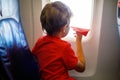 Little kid boy playing with red paper plane during flight on airplane Royalty Free Stock Photo