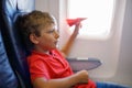 Little kid boy playing with red paper plane during flight on airplane Royalty Free Stock Photo