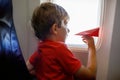 Little kid boy playing with red paper plane during flight on airplane Royalty Free Stock Photo