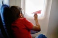 Little kid boy playing with red paper plane during flight on airplane Royalty Free Stock Photo