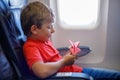 Little kid boy playing with red paper plane during flight on airplane Royalty Free Stock Photo