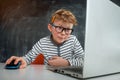 Little kid boy programming with laptop computer. Close up of the portrait of pupil in blue light blocking glasses. Child