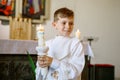 Little kid boy receiving his first holy communion. Happy child holding Christening candle. Tradition in catholic curch Royalty Free Stock Photo