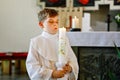 Little kid boy receiving his first holy communion. Happy child holding Christening candle. Tradition in catholic curch Royalty Free Stock Photo