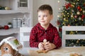 little kid boy in red pyjama holding decorated Christmas gingerbread men cookie