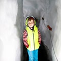 Little kid boy with safety helmets inside of glacier with ice tunnel. Schoolkid hiking and discovering mountain in Tirol