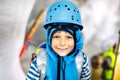 Little kid boy with safety helmets inside of glacier with ice tunnel. Schoolkid hiking and discovering mountain in Tirol