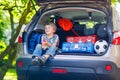 Little kid boy sitting in car trunk just before leaving for vaca Royalty Free Stock Photo