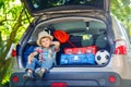 Little kid boy sitting in car trunk just before leaving for vaca Royalty Free Stock Photo