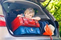 Little kid boy sitting in car trunk just before leaving for vaca Royalty Free Stock Photo