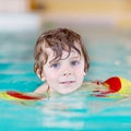 Little kid boy with swimmies learning to swim in an indoor pool Royalty Free Stock Photo