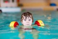 Little kid boy with swimmies learning to swim in an indoor pool Royalty Free Stock Photo