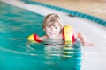 Little kid boy with swimmies learning to swim in an indoor pool Royalty Free Stock Photo