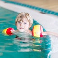 Little kid boy with swimmies learning to swim in an indoor pool Royalty Free Stock Photo