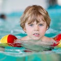 Little kid boy with swimmies learning to swim in an indoor pool Royalty Free Stock Photo