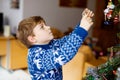 Little kid boy taking down holiday decorations from Christmas tree. Family after celebration remove and dispose tree Royalty Free Stock Photo