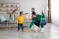 Little kid boy watching her mother mopping the floor after him. Woman wiping the floor with rag next to her baby Royalty Free Stock Photo
