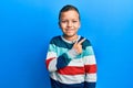 Little kid boy wearing striped sweater smiling cheerful pointing with hand and finger up to the side Royalty Free Stock Photo