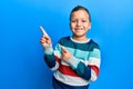 Little kid boy wearing striped sweater smiling and looking at the camera pointing with two hands and fingers to the side Royalty Free Stock Photo