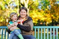 Little kid boy and young father sitting together in colorful clothing on bench in park. Cute healthy child and dad Royalty Free Stock Photo