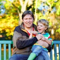 Little kid boy and young father sitting together in colorful clothing on bench in park. Cute healthy child and dad Royalty Free Stock Photo