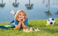 Little kid chessman play chess game, checkmate. Child playing chess in spring park.