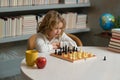 Little kid chessman play chess game, checkmate. Child playing chess in the room. Kids early development. Boy kid playing