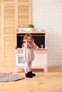 Little kid concept. Adorable smiling toddler girl at play kitchen in light room Royalty Free Stock Photo