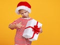 Little kid disappointed preschool boy in Santa hat pointing with finger on Xmas gift box in his hand Royalty Free Stock Photo