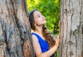 Little kid dreamer with long wavy hair and beauty look dream at tree trunk in summer park, future Royalty Free Stock Photo