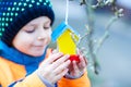 Little kid hanging bird house on tree for feeding in winter Royalty Free Stock Photo