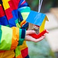 Little kid hanging bird house on tree for feeding in winter Royalty Free Stock Photo