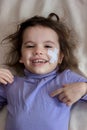 Little kid girl after accident with adhesive band on face laughing.