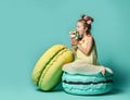 Kid girl in bright yellow dress have fun at birthday party fun. Sits on big macaroon cake sweets eating big ice-cream Royalty Free Stock Photo