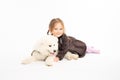 Little kid girl in dress looking at the camera, child hugging her samoyed puppy while liying on the ground