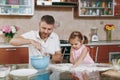Little kid girl help man to cook Christmas ginger cookies and sprinkling flour in kitchen. Happy family dad, child