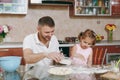 Little kid girl help man to cook lazy dumplings sprinkling flour at table. Happy family dad, child daughter cooking food