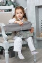 Little kid girl sitting in chair with christmas gift box. Royalty Free Stock Photo