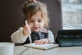 Little kid girl writing or drawing with pen in scetch book