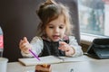 Little kid girl writing or drawing with pen in scetch book