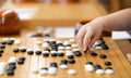 Little kid hand playing Chinese Go or Weiqi game board