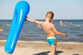 Little kid holding an inflatable mattress on the beach on hot summer day Royalty Free Stock Photo