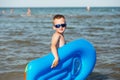 Little kid holding an inflatable mattress on the beach on hot summer day. Royalty Free Stock Photo