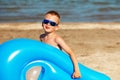 Little kid holding an inflatable mattress on the beach on hot summer day. Royalty Free Stock Photo