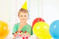 Little kid in holiday hat with festive cake and balloons Royalty Free Stock Photo